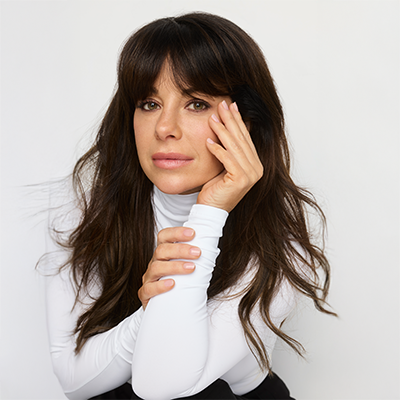 Marie-Claude_Savard vêtue d’un col roulé blanc, posant la tête contre sa main avec un regard serein